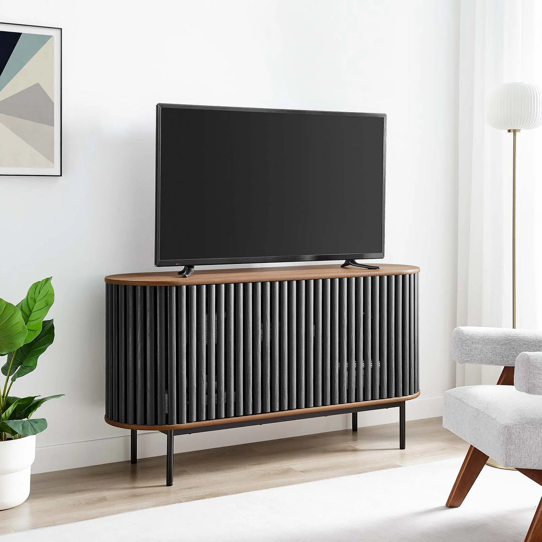 Credenza negra ovalada con madera estriada color nogal Veron en una sala como mueble para TV.