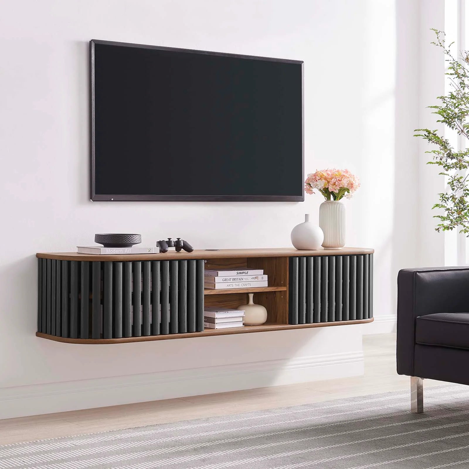Mueble de pared negro ovalado estriado color nogal para TV Veron en una sala con una televisión.