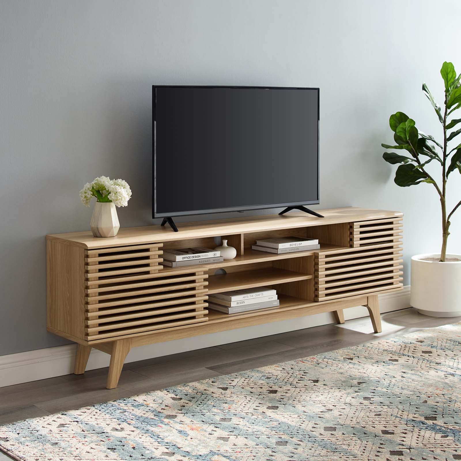 Mueble multimedia de 71” para TV Niklas color roble en una sala.