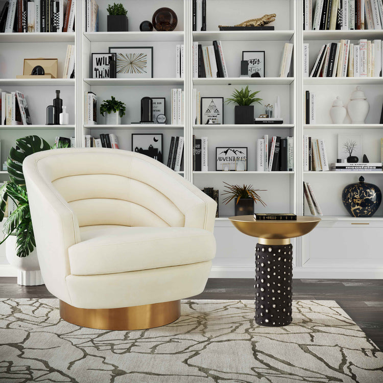 Silla de acento de terciopelo crema y base dorado cepillado Ara en una sala.