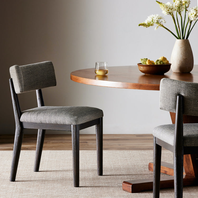 Silla de comedor de Parawood quemado Derma frente a un comedor redondo.