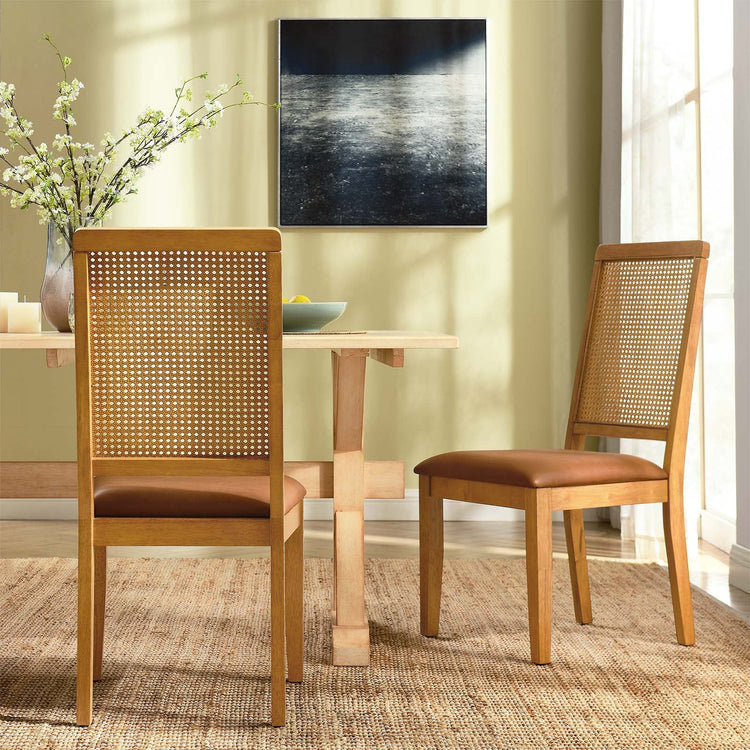 Silla de comedor de piel vegana color bronceado marco natural  con ratán sintético Enzo en un comedor.