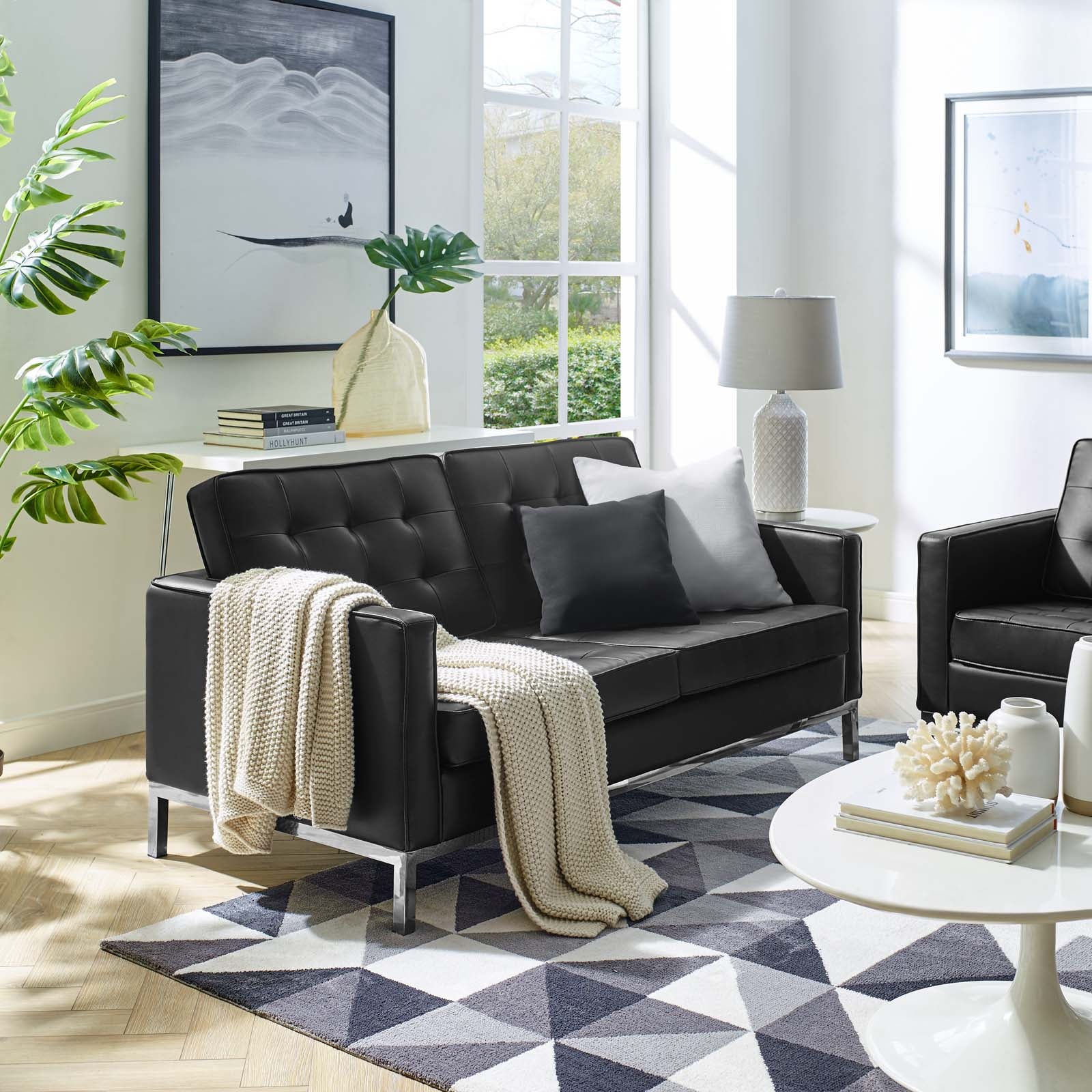 Sofá de dos plazas capitoné tapizado de piel sintética negra Davoli en una sala de estar.