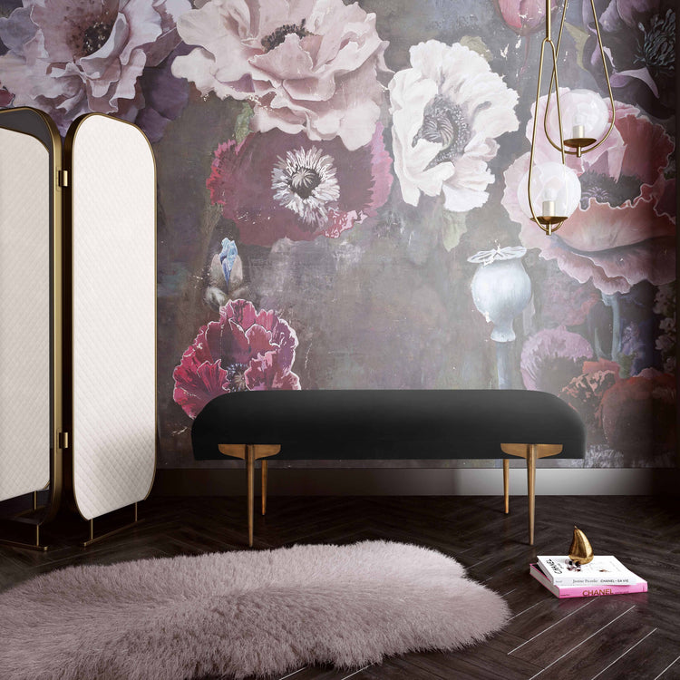Banca de terciopelo para recámara Alexine en una recámara moderna con un tapiz floreado, unas revistas en el piso y un tapete moderno.